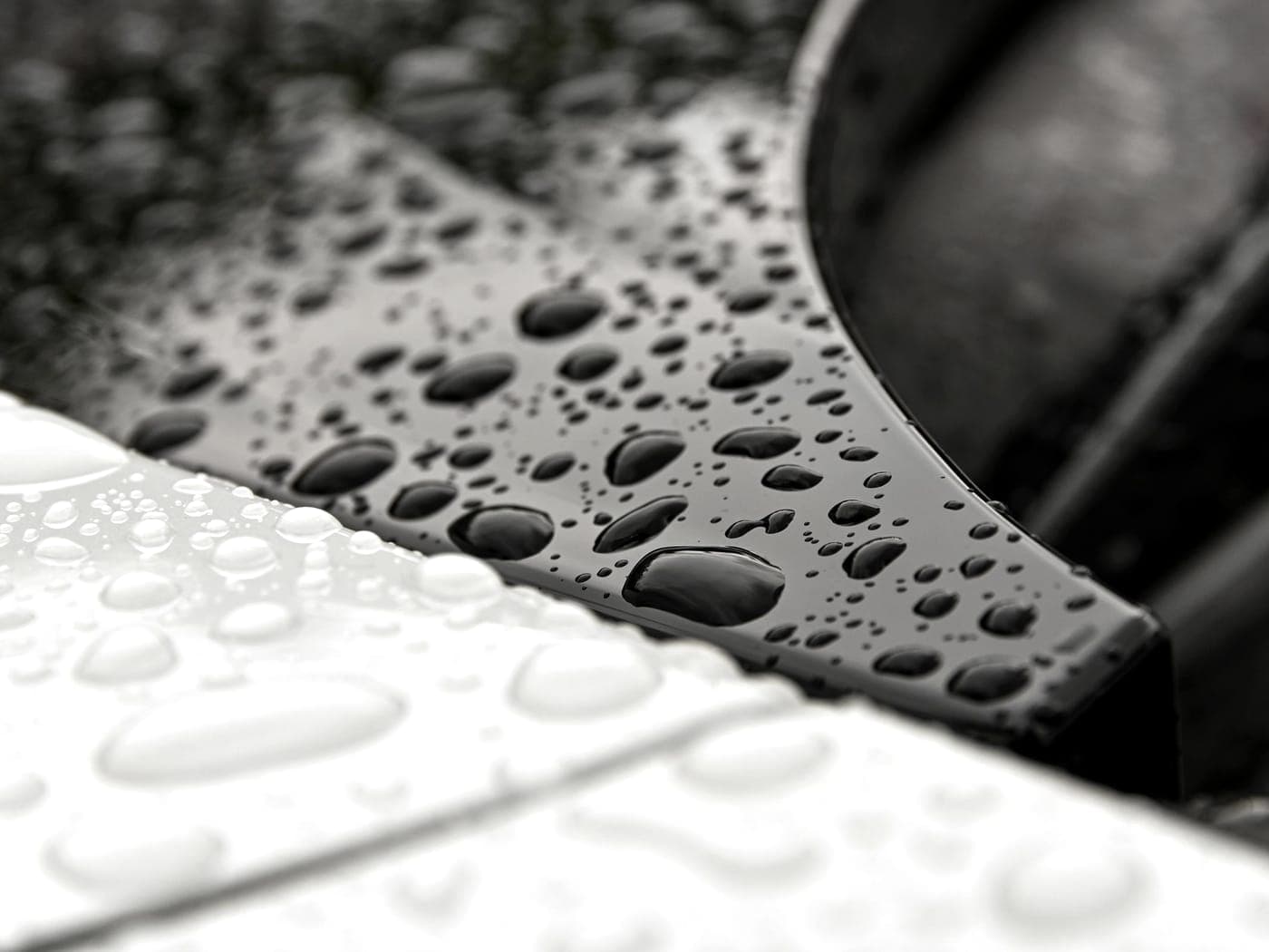 Macro view of water beading on a dark, coated metallic panel