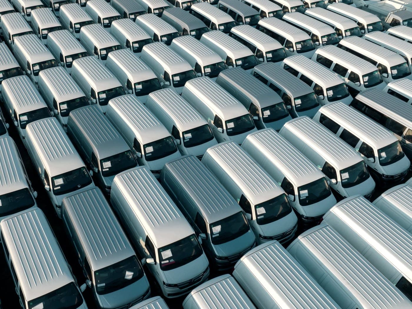 Rows of white work vans parked at a commercial yard