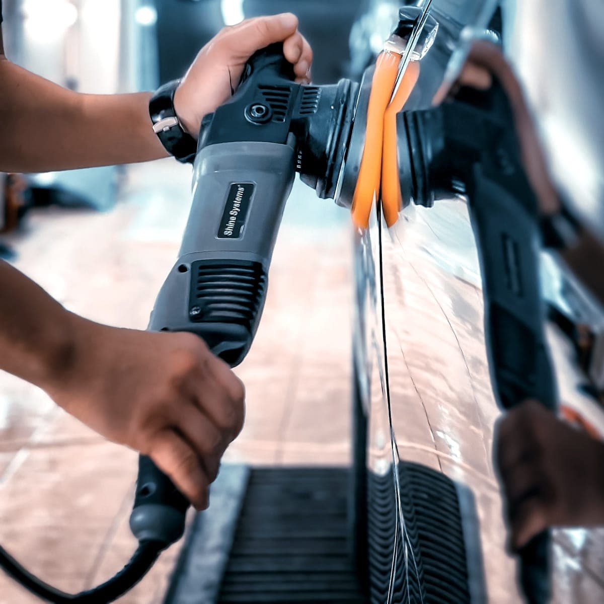 Machine polisher working along the edge of a painted panel